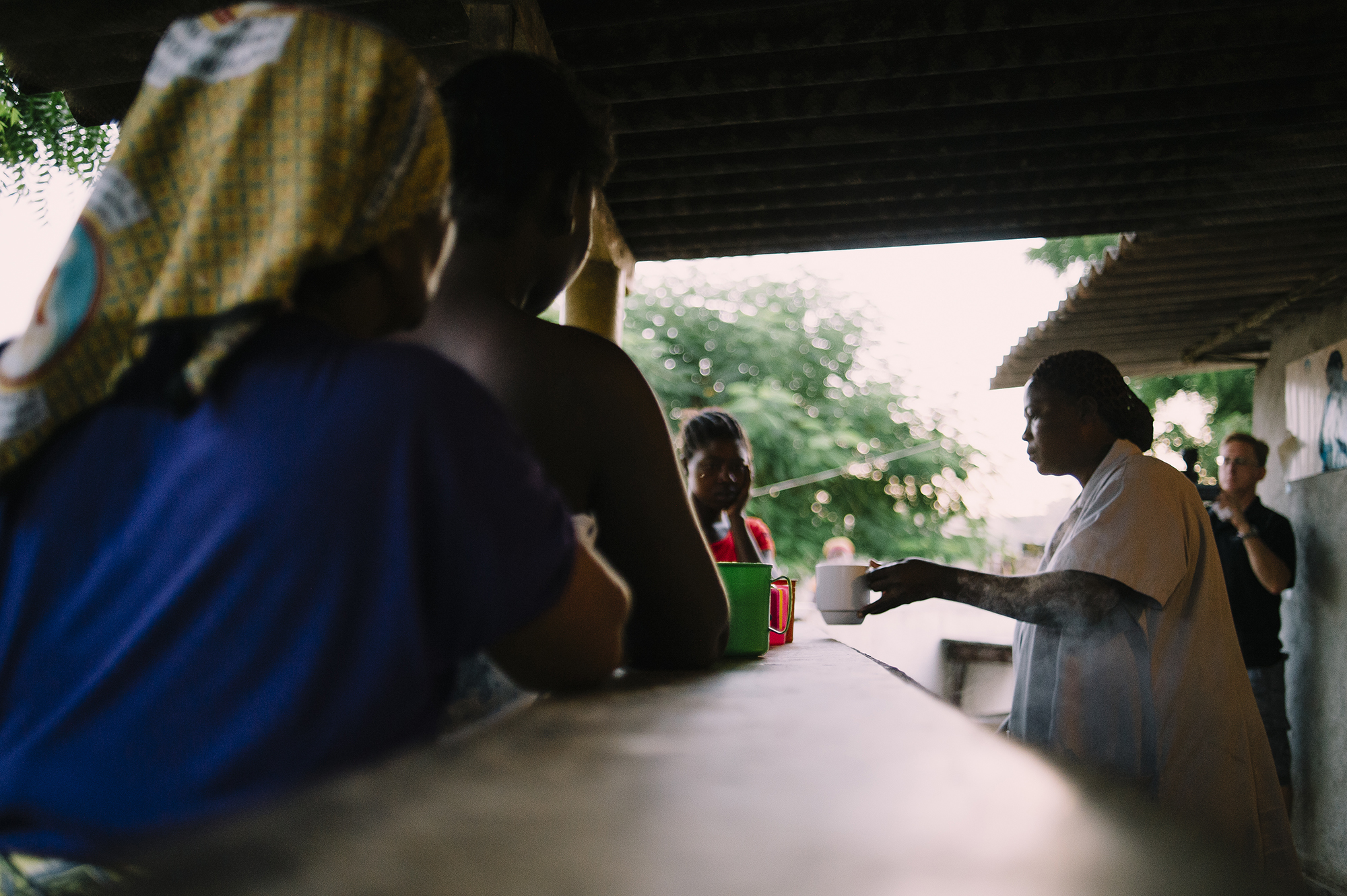 Mothers and healthcare workers in a malnutrition clinic interacting during feeding time, with therapeutic milk and colorful cups visible, highlighting community support and care for infants.