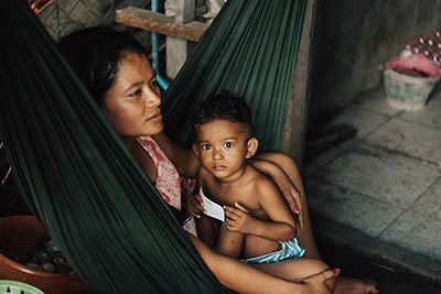 Mother and child resting in a hammock, conveying warmth and security, reflecting themes of care and hope in challenging environments.