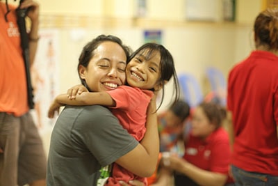Stars - Title Page - a team trip volunteer hugging a toddler girl.