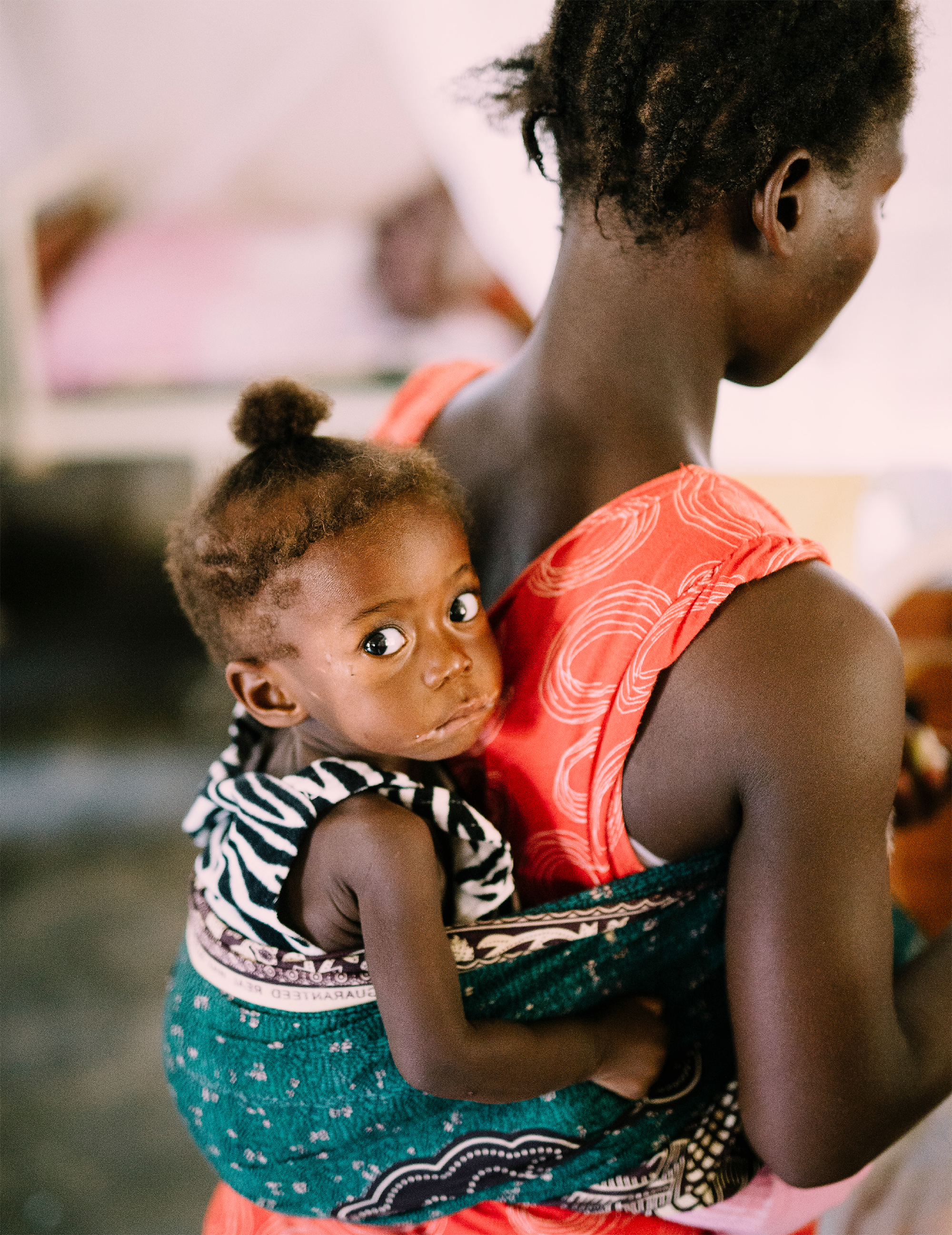 Mother carrying child in a traditional wrap, showcasing care and support for vulnerable children, relevant to Saving Moses' mission in the 2017 annual report.