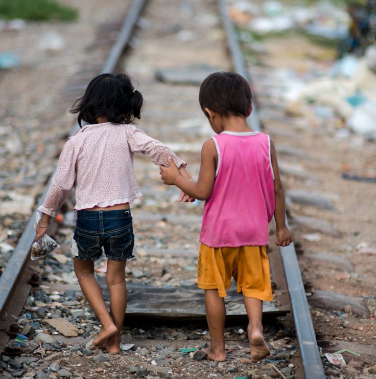Two children walking hand in hand along a railway track, symbolizing vulnerability and the need for safety, relevant to Saving Moses' NightCare initiative for at-risk babies and toddlers in India.