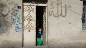 Born in Refuge: Helping the Helpless - a toddler in Syria standing in a doorway.