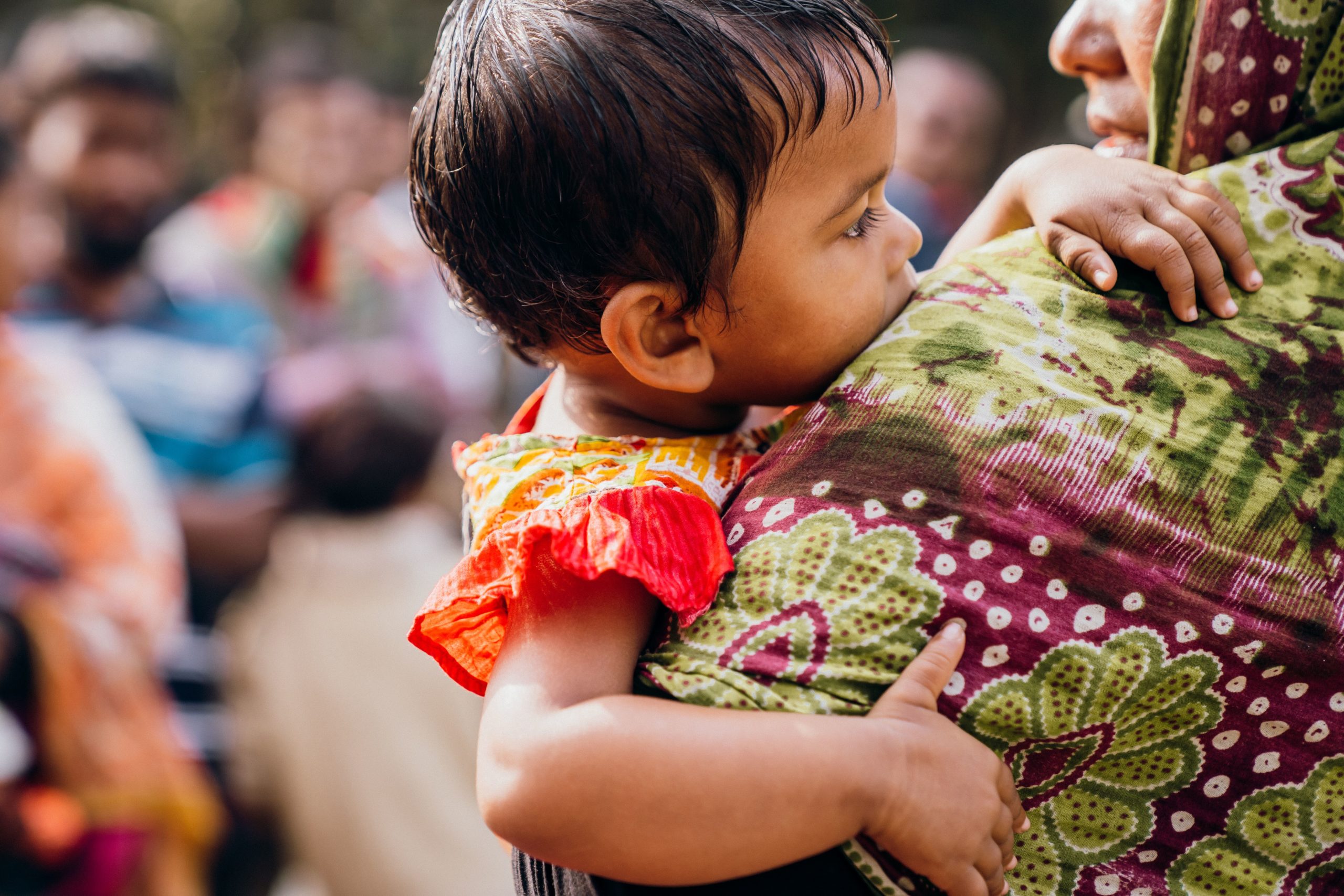 A baby of a sex worker holding onto her mother.