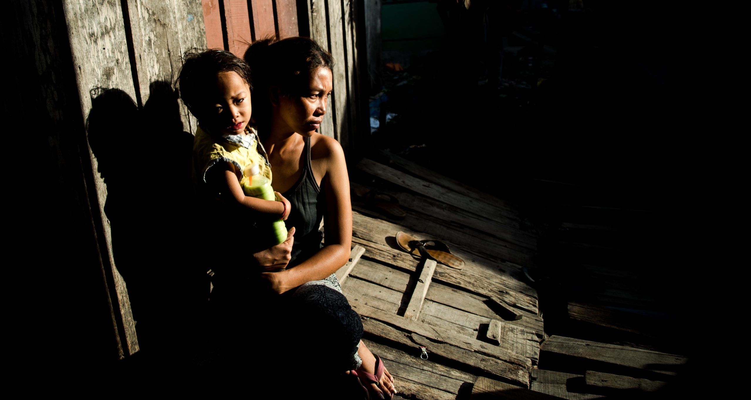Mother holding child in a vulnerable setting, emphasizing the need for support for babies of sex workers, highlighting themes of care and protection.