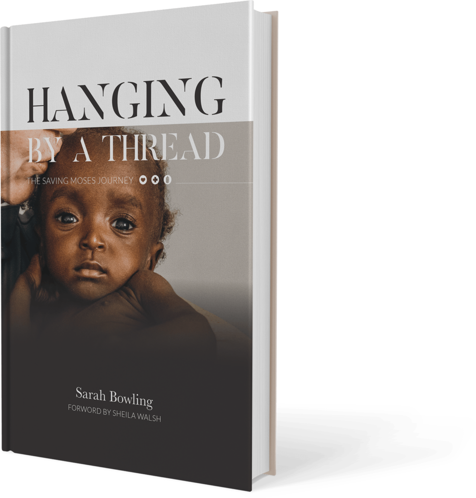 Book IMage Book cover of "Hanging by a Thread" by Sarah Bowling, featuring a close-up of a baby with a serious expression, emphasizing themes of child welfare and hope related to Saving Moses initiatives.