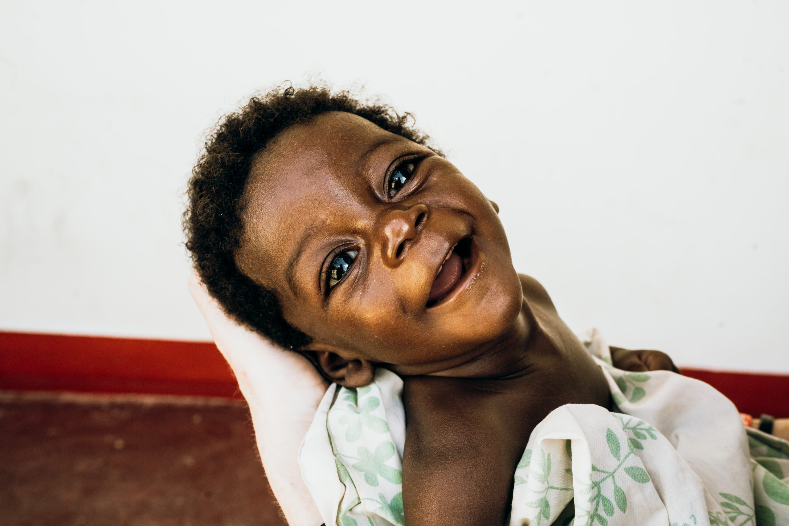 Smiling baby in a caregiver's arms, showcasing joy and innocence, representing the mission of Saving Moses to aid vulnerable children.
