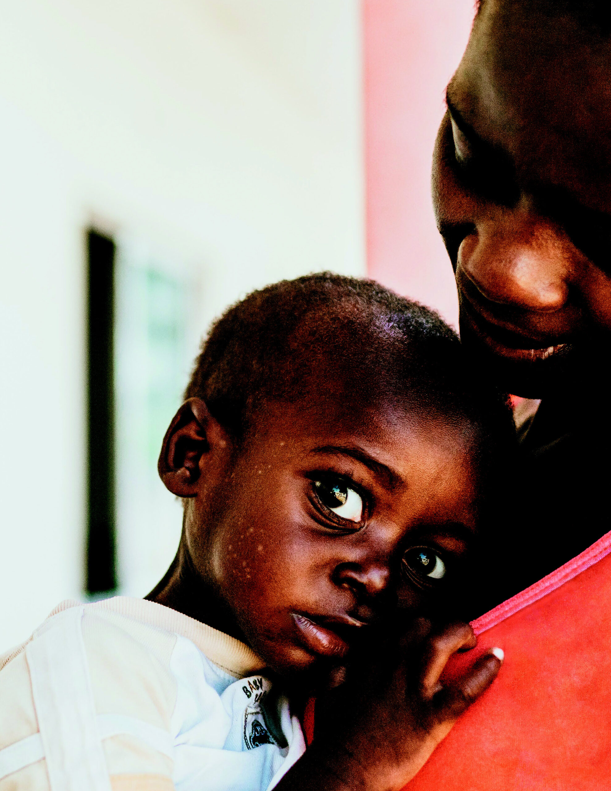 Child clinging to caregiver, showcasing vulnerability and connection, reflecting themes of support and care in Saving Moses' 2020 Annual Report.