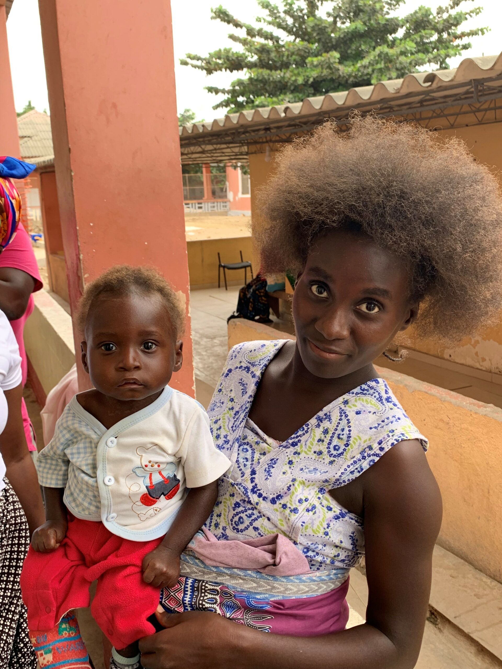 Mother holding a baby in a casual setting, highlighting themes of child welfare and maternal care related to malnutrition and child development.