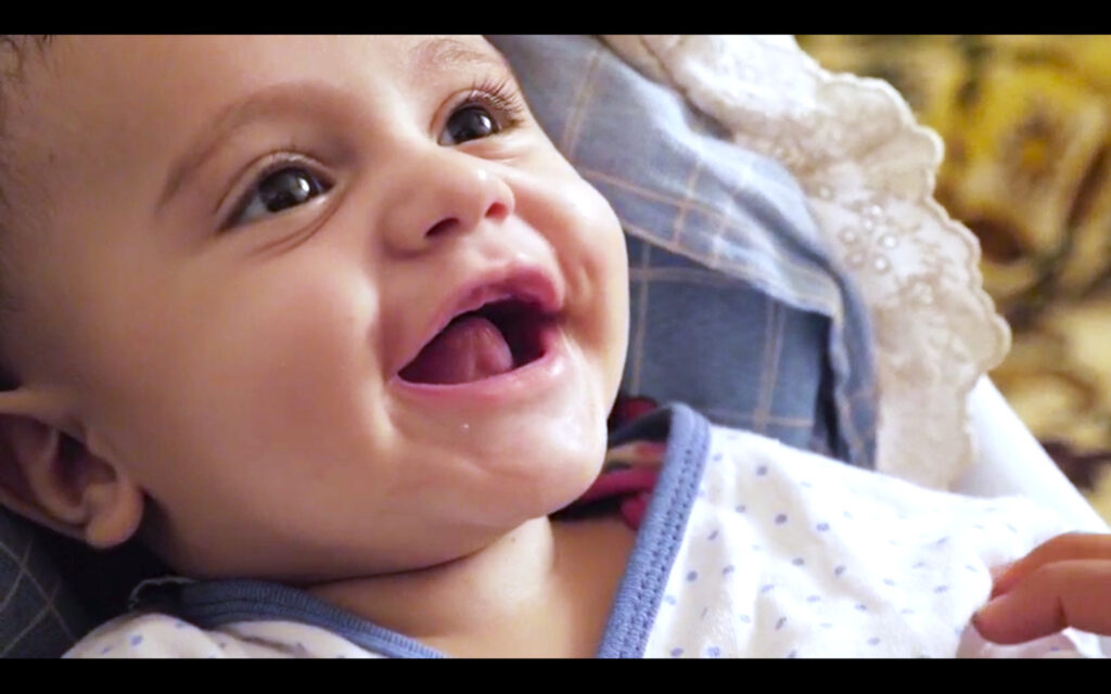Smiling baby in a cozy setting, representing hope and innocence amidst discussions of infant mortality and challenges in conflict zones like Afghanistan.