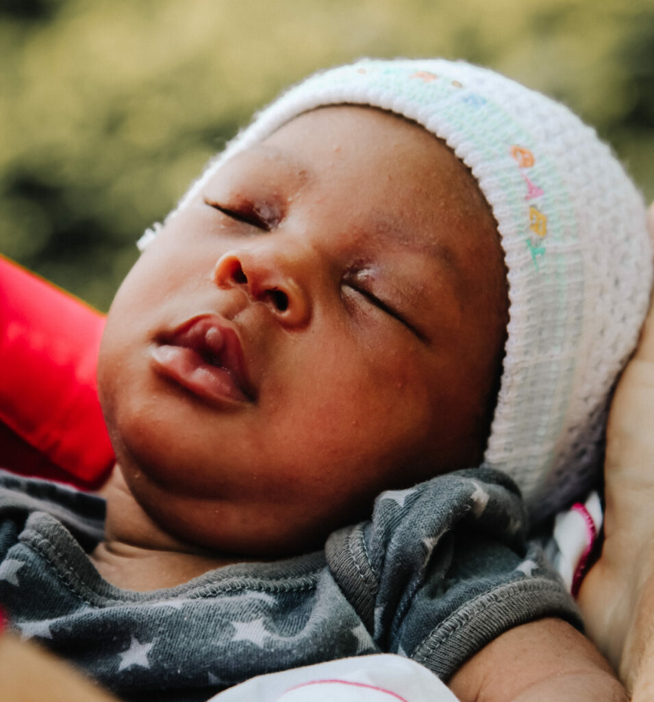 Infant sleeping peacefully, wearing a knitted hat, representing vulnerable babies in Angola facing malnutrition and healthcare challenges.