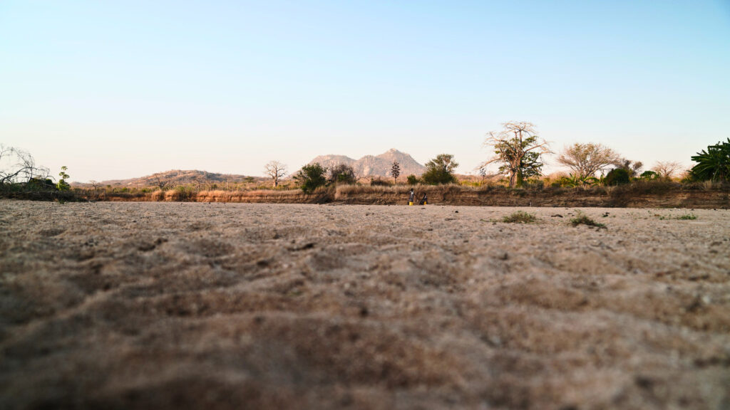 Dry landscape in Angola with sparse vegetation and distant mountains, highlighting the effects of drought and environmental crisis.