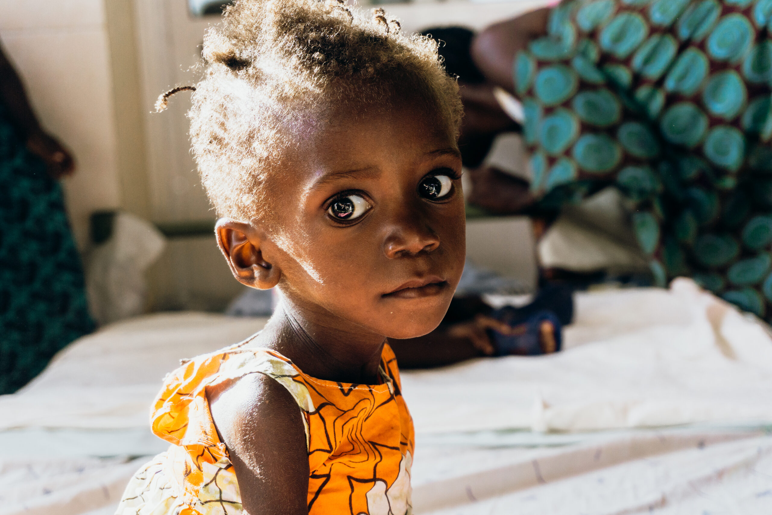 SMF-03764 Child with expressive eyes in a brightly colored dress, representing vulnerable infants in need of care and support, emphasizing the mission of Saving Moses to aid malnourished and at-risk children.
