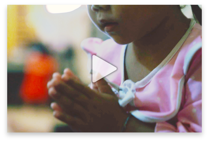 Child in pink clothing with clasped hands, symbolizing hope and prayer, representing the mission of Saving Moses to support vulnerable children.