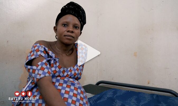Pregnant woman in a clinic setting, wearing a traditional patterned dress, conveying hope and resilience in the context of malnutrition support by Saving Moses.