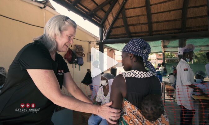 Woman interacting with a mother and child at a malnutrition clinic, highlighting Saving Moses' efforts to support malnourished families.