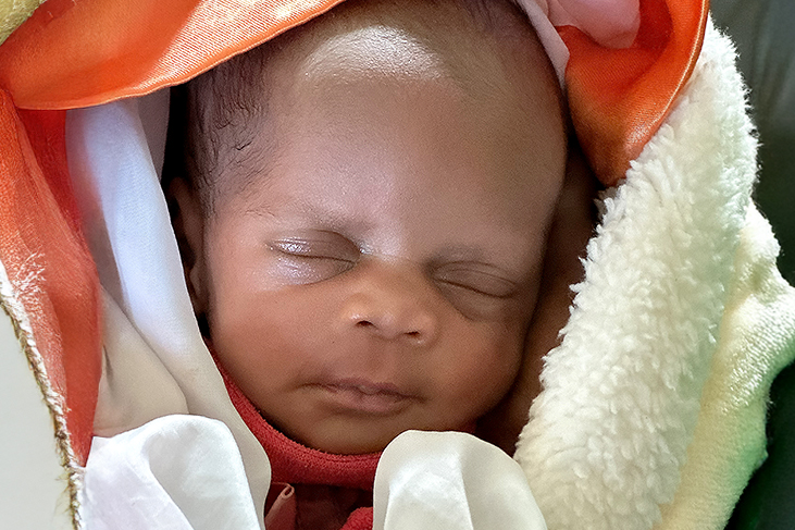 Newborn baby swaddled in colorful blankets, representing hope and the need for healthcare support in rural areas.