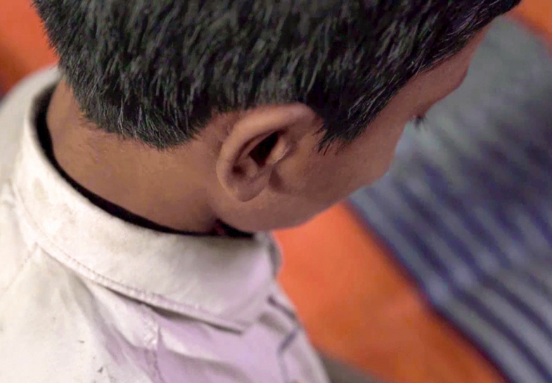 Child with short black hair looking down, wearing a white shirt, symbolizing hope and vulnerability in the context of Saving Moses' mission to support babies in need.