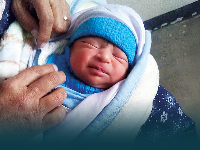 Newborn baby wrapped in a blanket, being held gently by a caregiver, emphasizing the care and safety of infants during childbirth.